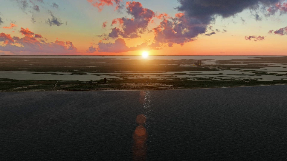 Sunset over a coastal area with water and land.